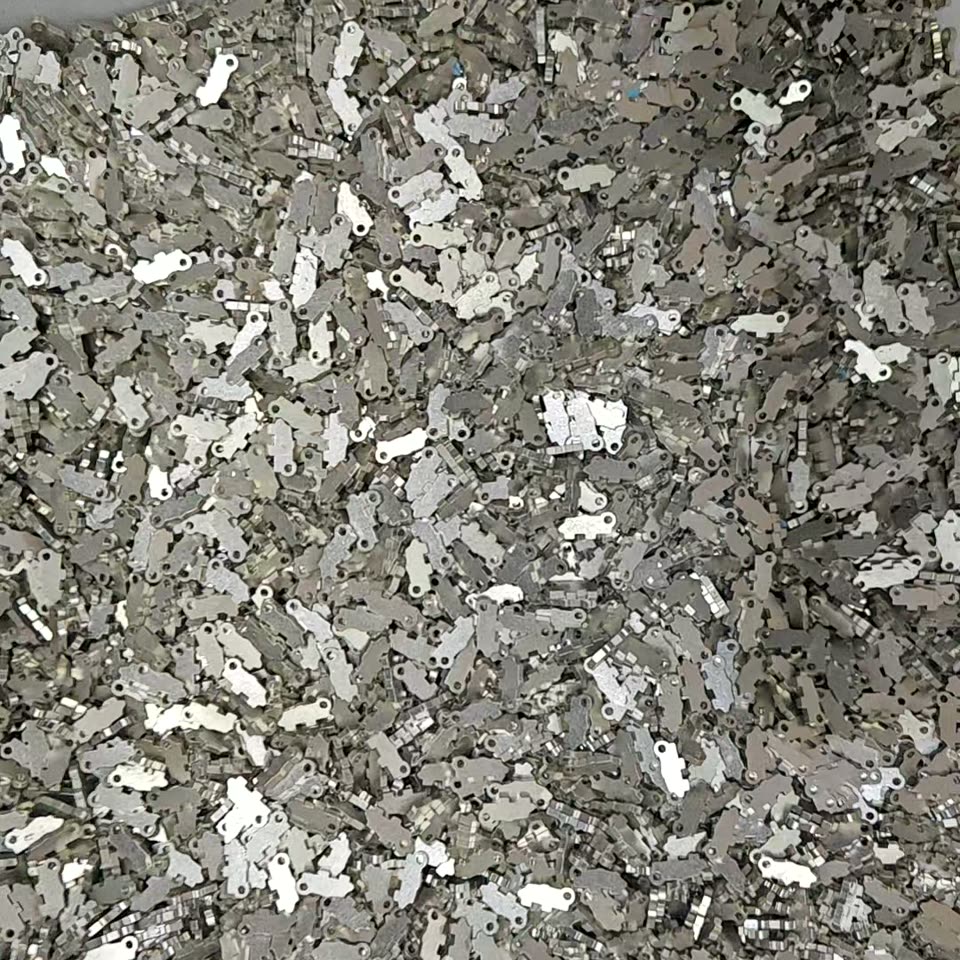A production batch of nickel-finish temple hinge halves, fresh off the bench